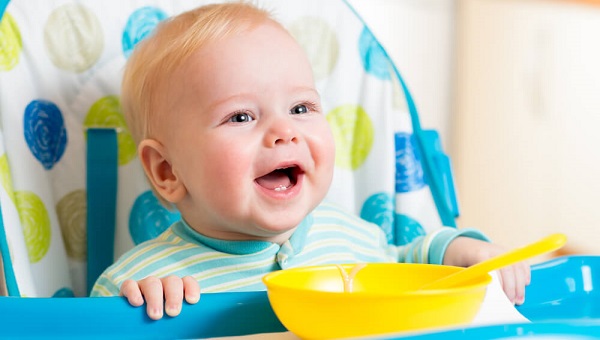 smiling baby eating food on kitchen