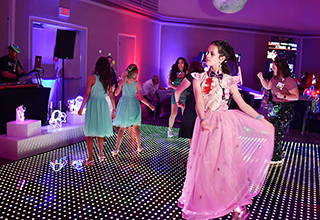 A young girl in a pink dress danced on a colorful dance floor.