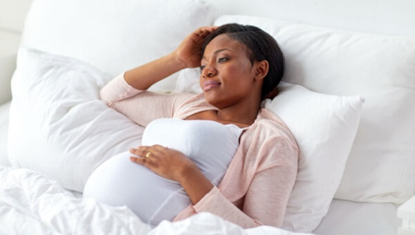 young black pregnant woman laying on bed