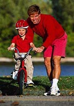 Picture of a father teaching his young son how to ride a bicycle