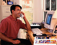 Picture of a man working on the computer, talking on the phone
