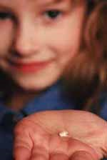 Picture of a young girl holding a tooth in her palm.