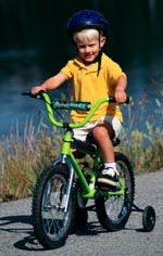 Picture of young boy, with a helmet, riding a bicycle