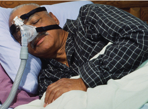 African American man in bed wearing a CPAP mask.