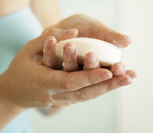 Closeup of hands holding sudsy bar of soap.