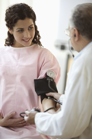 Health care provider taking pregnant woman's blood pressure.