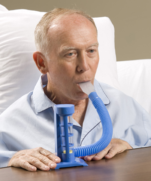 Man in hospital bed using incentive spirometer.