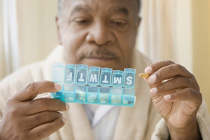 Man taking pill out of pill organizer.