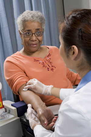 Health care provider taking blood sample from woman's arm.