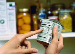 Hands holding can with finger pointing to nutrition label.