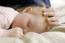 Photo of sleeping toddler, parent storking its head.