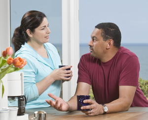 Man and woman talking over coffee at kitchen counter.