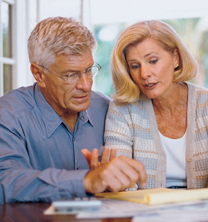 Man and woman sitting at table looking at paperwork.