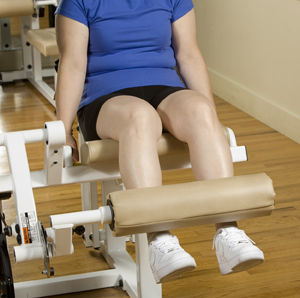 Woman doing leg extensions on exercise equipment.