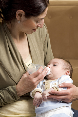 Mother feeding newborn baby with bottle.