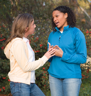 Two young women having a serious conversation outdoors.