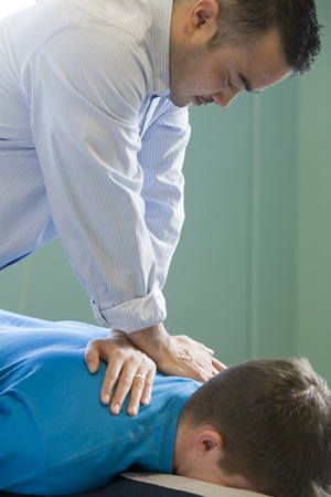 Chiropractor working on neck, shoulder area of man lying on table.