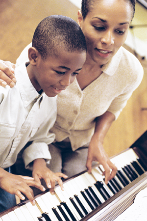 Young boy and woman playing a piano together.