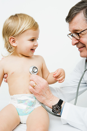 Doctor with stethoscope listening to toddler's chest.