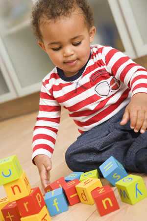Toddler sitting on floor playing with blocks.
