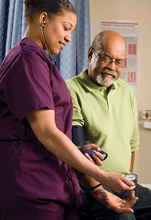 Nurse checking blood pressure of mature male patient.