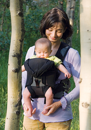Woman walking in forest with baby in front carrier.