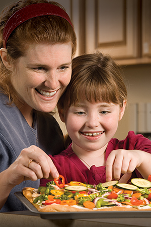 Woman and girl preparing healthy food in kitchen.