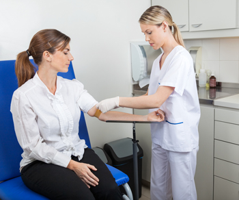 Healthcare provider drawing blood from woman's arm.