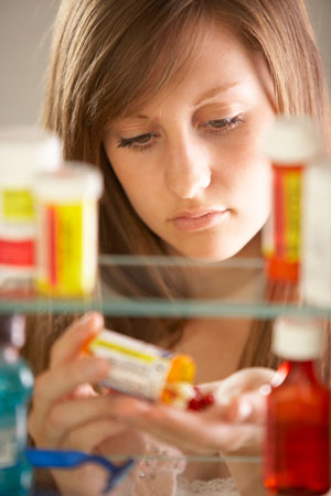 Young woman taking prescription meds from a medicine cabinet