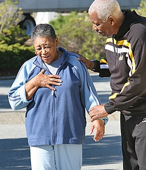 Senior African-American woman in pain with hand on chest.