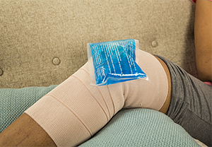Elevated bandaged knee with ice pack.