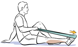 Man sitting on floor holding ends of elastic band wrapped around left foot, pointing toes away from him. 