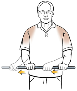 Man standing doing external rotation shoulder exercise with wand.