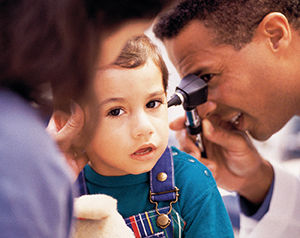 Healthcare provider examining toddler’s ear with otoscope.