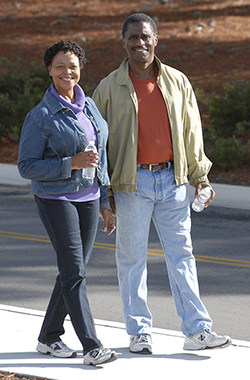 Man and woman walking on sidewalk.