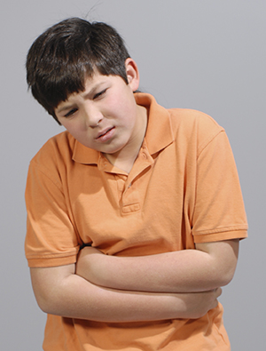 Boy holding stomach, looking distressed.