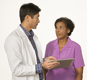 Doctor and patient talking, doctor holding tablet.