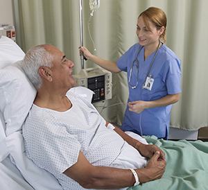 Healthcare provider caring for man in hospital bed.