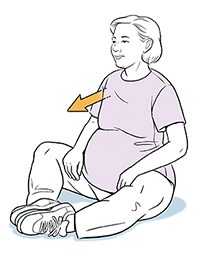 Pregnant woman sitting cross-legged, twisting torso to side.