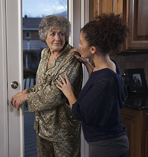 Woman preventing senior woman from going out kitchen door.