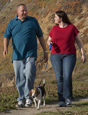 Man and woman walking with their dog.