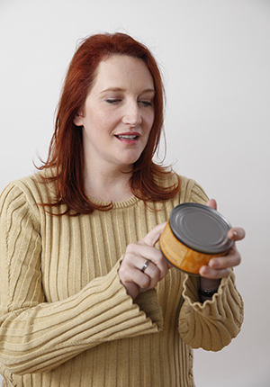 Woman reading nutrition label on can.