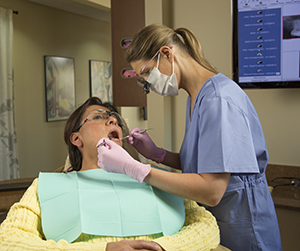 Dental hygienist performing cleaning on a patient.