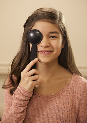 Girl holding cover over eye during eye exam.