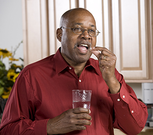 Man taking a pill with a glass of water