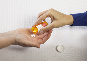Closeup of woman's hand putting pills in another woman's hand.