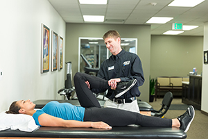 Physical therapist working with woman on leg stretches.