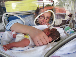 Woman looking at baby in incubator.