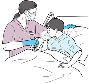 Boy in hospital bed coughing into tissue. Healthcare provider standing beside bed wearing face shield, mask and gloves.