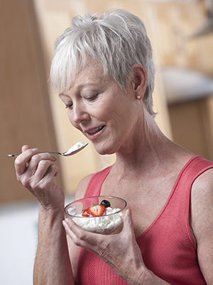 Mature woman eating a bowl of cottage cheese and fruit